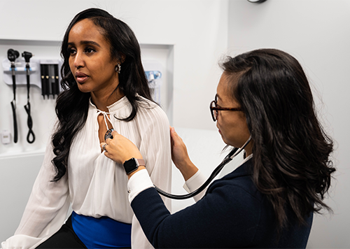 Woman in exam room with a doctor listening to her breathing