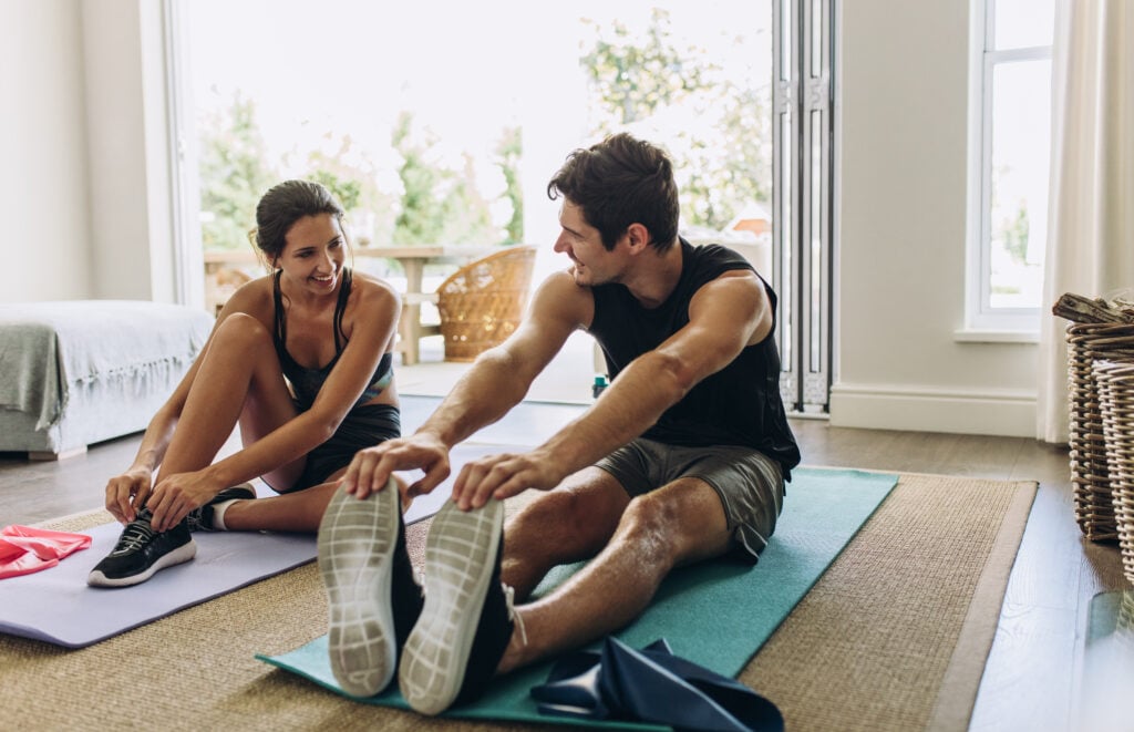 man and woman stretching on yoga matts in their living room