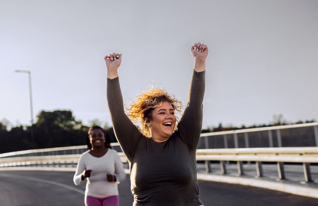 a woman with her arms raised in joy after a workout